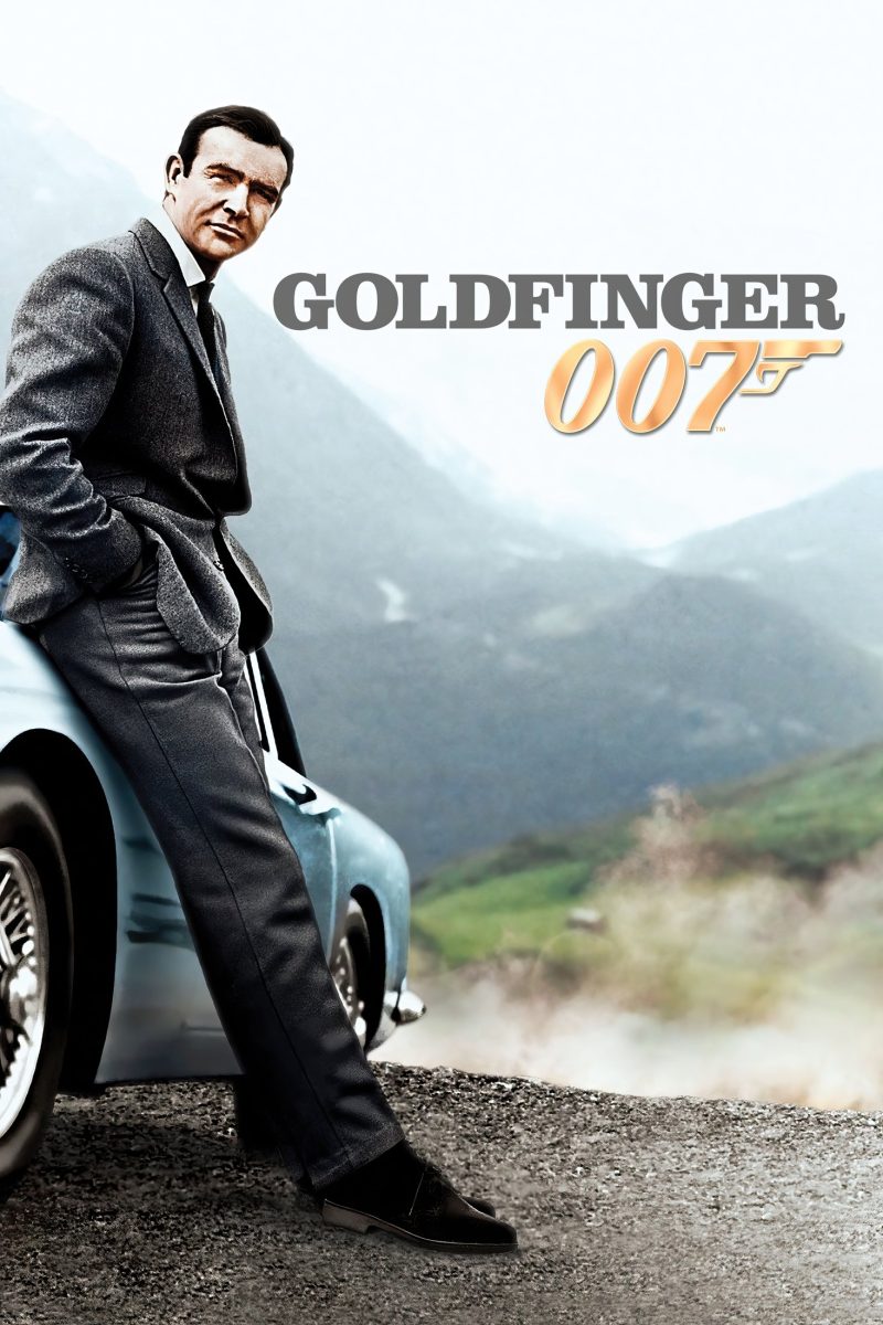 Πόστερ ταινίας Goldfinger – άντρας με τουίντ σακάκι ακουμπά σε ασημί σπορ αυτοκίνητο σε ορεινό δρόμο — εικόνα 1 από 6